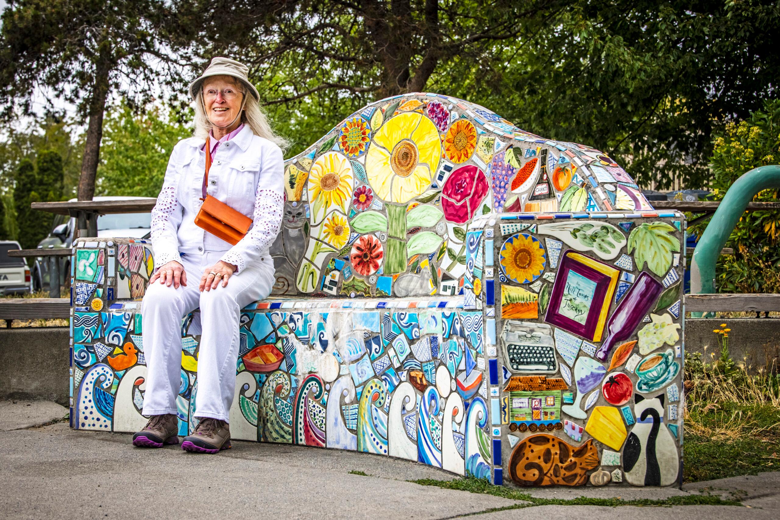 A woman sits on a colorful decorative bench at Lynn Street Mini Park.
