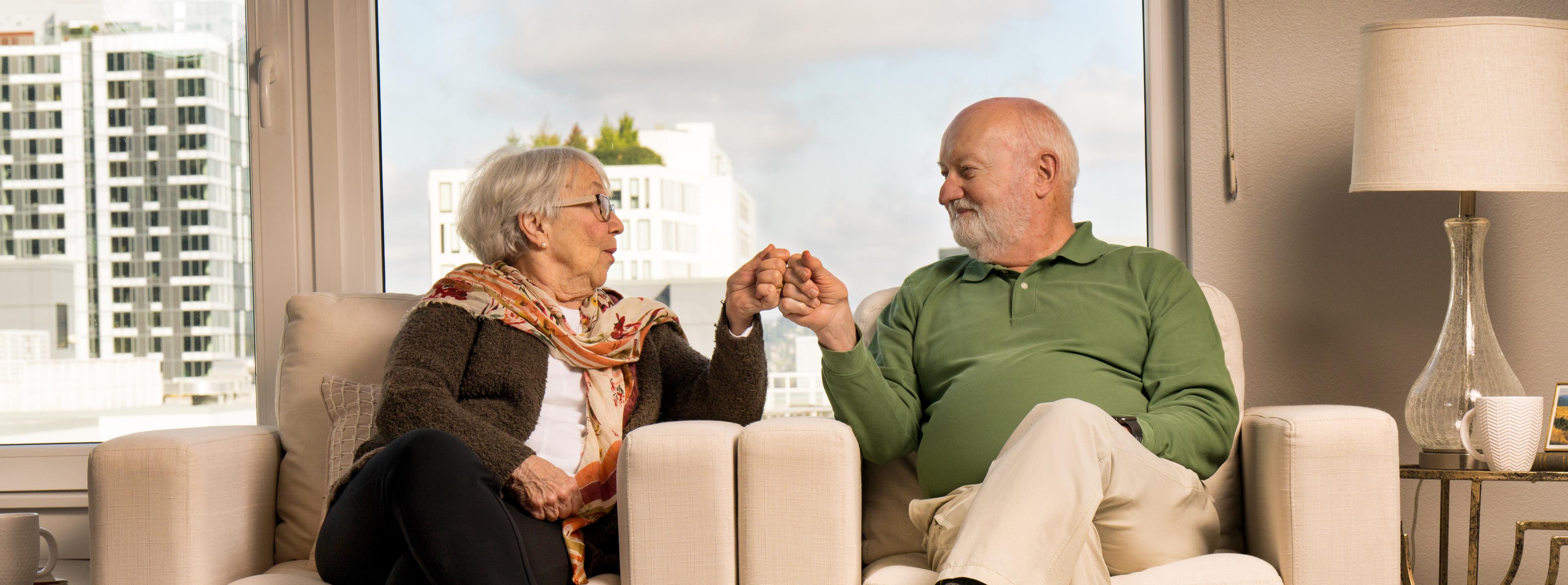 Two older adults fist bumping in an apartment.